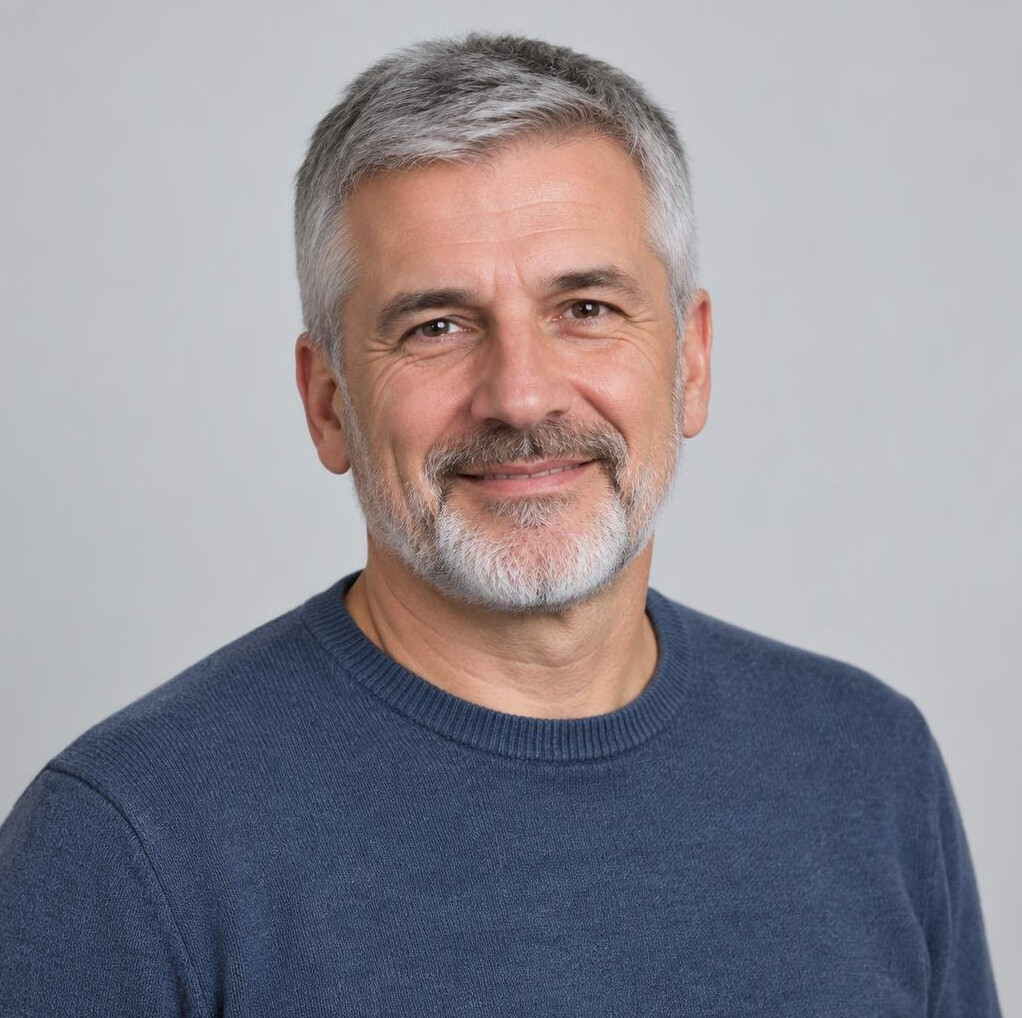Studio portrait of an older Croatian man with gray hair and a beard, smiling